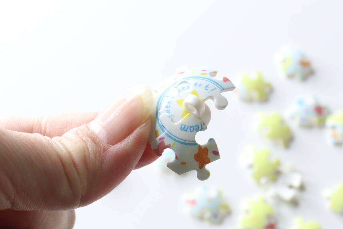指で球体パズルのピースを一つ持っている様子。ピースのカーブと絵柄がよくわかる。