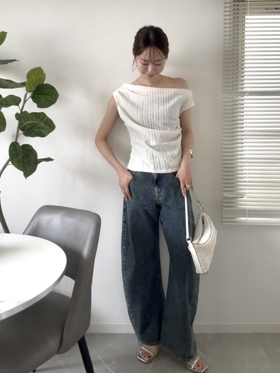白いワンショルダートップスと3Dバレルジーンズを着た女性 白いワンショルダートップスと3Dバレルジーンズを着た女性