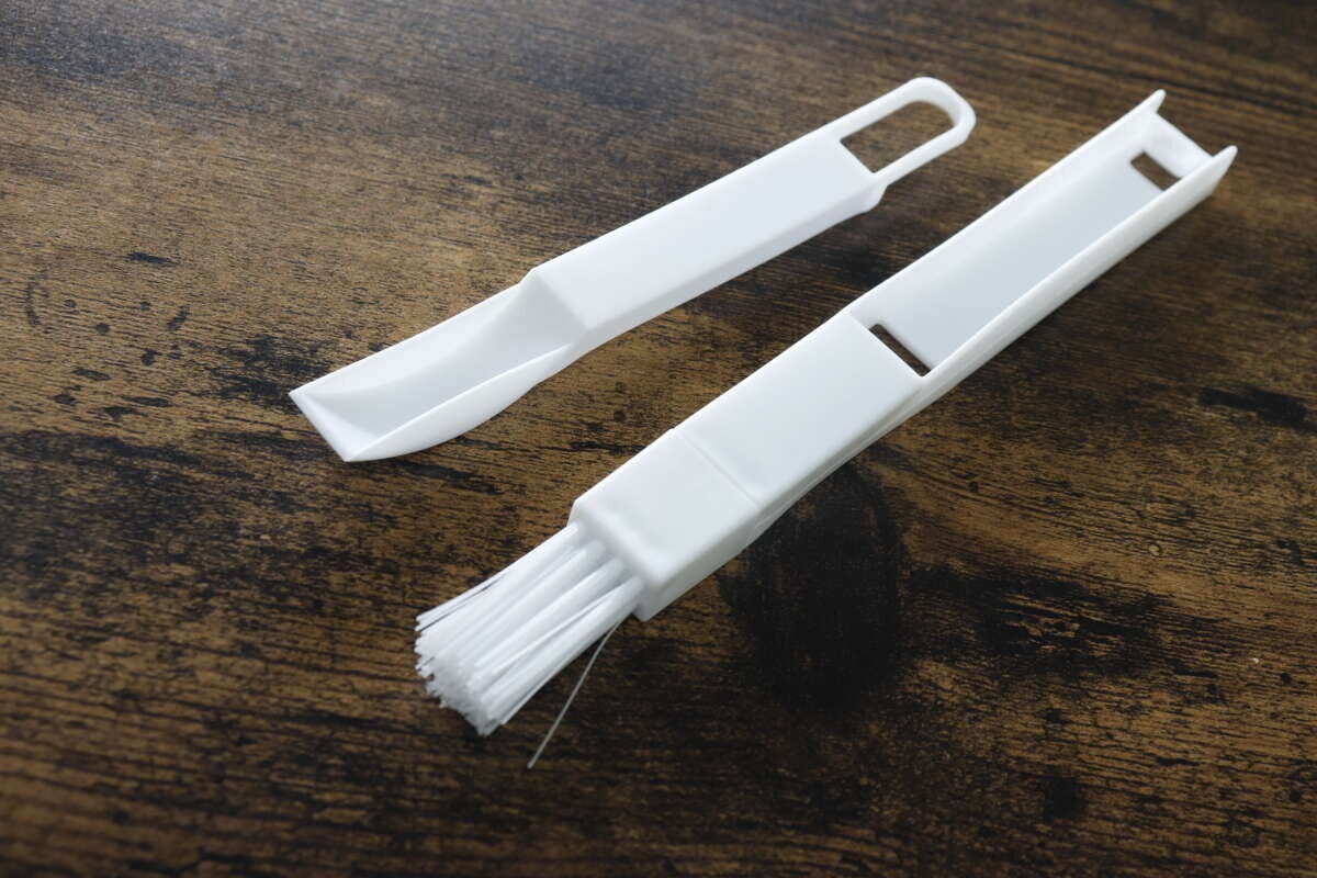 白いサッシ用ほうきとちりとりが分離され木目調のテーブルに並ぶ 白いサッシ用ほうきとちりとりが分離され木目調のテーブルに並ぶ