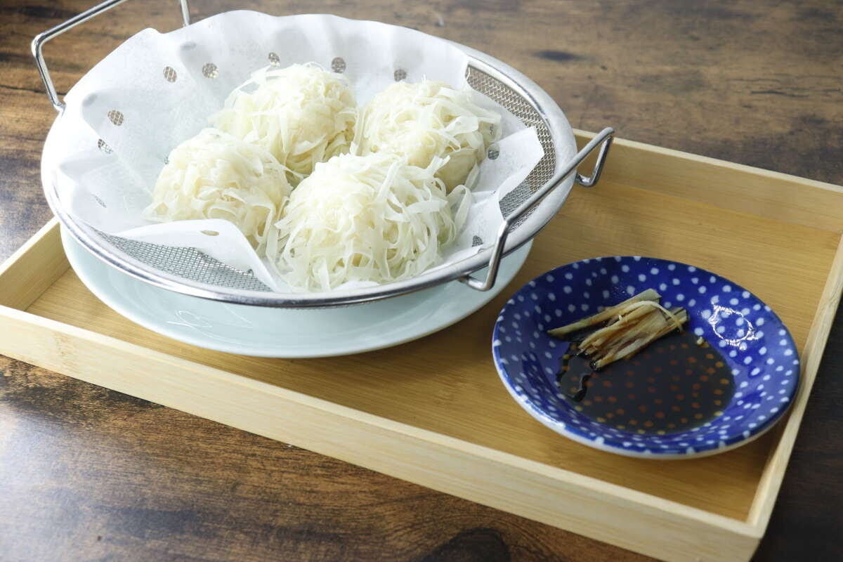 蒸し上がった焼売のような料理が浅型ザルに入り食卓に置かれている