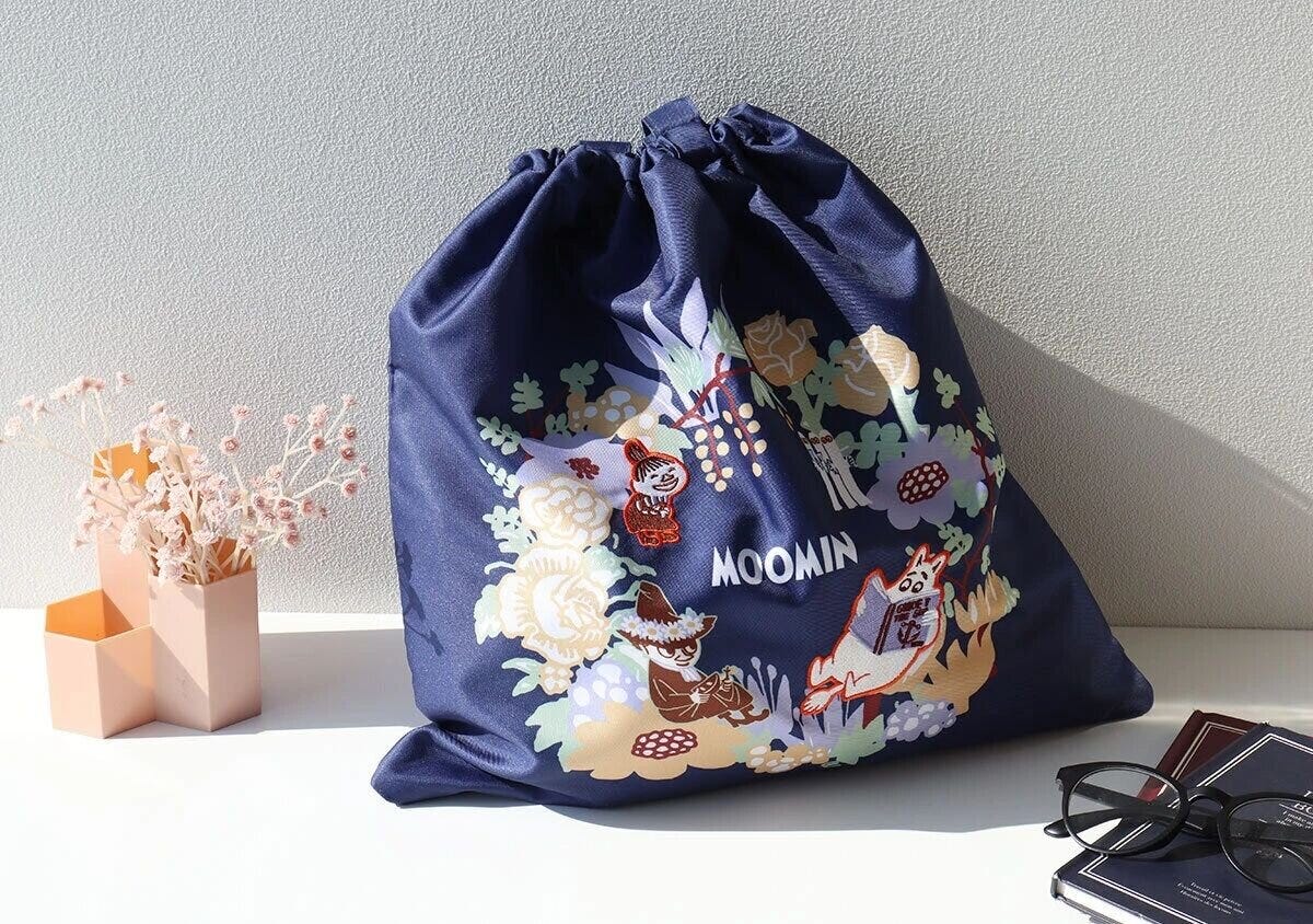 ネイビー地にフラワープリントとムーミンキャラクターイラストが描かれた大型巾着トートバッグの正面写真 ネイビー地にフラワープリントとムーミンキャラクターイラストが描かれた大型巾着トートバッグの正面写真