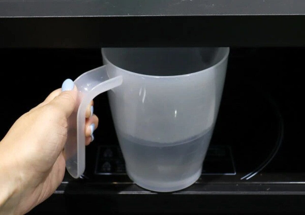 女性が水を入れた万能メジャーカップを電子レンジに入れようとしている 女性が水を入れた万能メジャーカップを電子レンジに入れようとしている