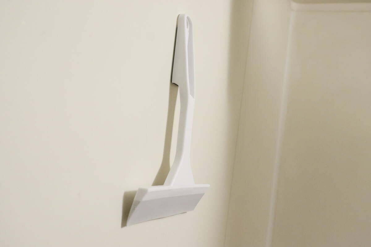 白い水切りワイパーが浴室の壁にマグネットで貼り付けられて収納されている様子 白い水切りワイパーが浴室の壁にマグネットで貼り付けられて収納されている様子