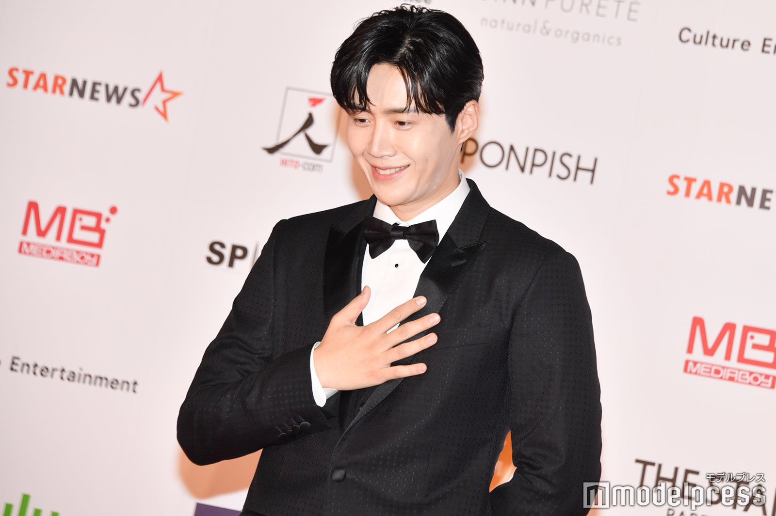 ポーズを決め終わりホッとする仕草を見せるキム・ソンホ （C）モデルプレス