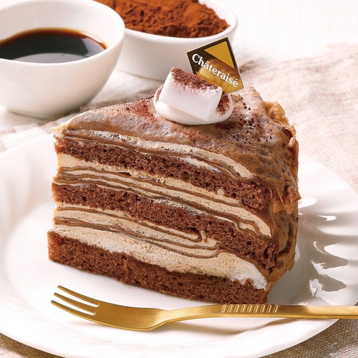 金色のフォークが添えられたチョコレート色のクレープケーキの断面 金色のフォークが添えられたチョコレート色のクレープケーキの断面