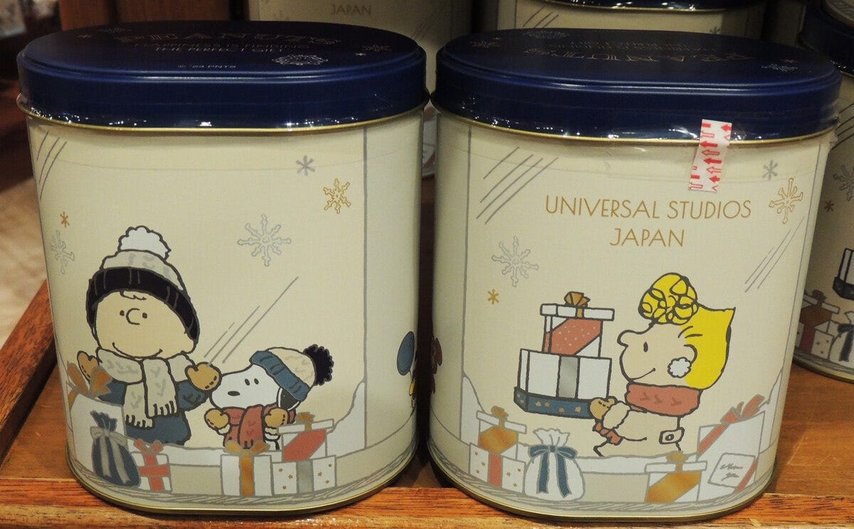 缶のデザインは、ホリデーショッピングを楽しむスヌーピーとチャーリー・ブラウン。逆側ではサリーもショッピング中です