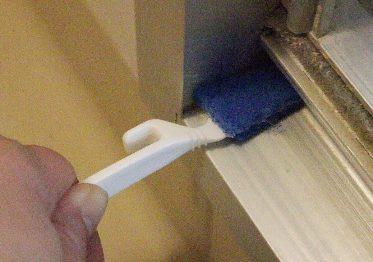 手ですきま用スティックを使いドアレールの隙間を掃除している様子 手ですきま用スティックを使いドアレールの隙間を掃除している様子