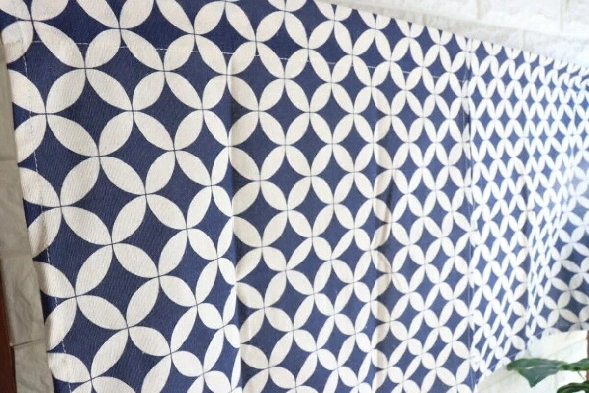 七宝柄の紺色と白の和柄のれんが突っ張り棒に吊り下げられている 七宝柄の紺色と白の和柄のれんが突っ張り棒に吊り下げられている