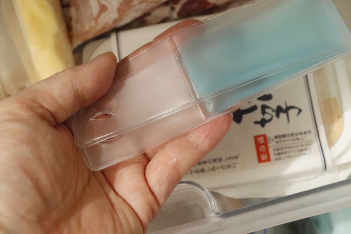 女性の手が、冷凍庫の引き出しにアイスパックを入れている