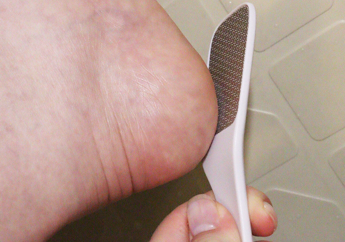 女性が自分のガサガサしたかかとにダイソーのかかとやすりを当ててケアしている様子