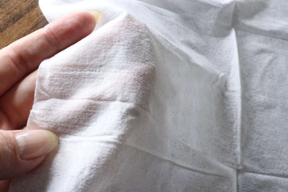 女性の指でウェットシートの厚みと質感を確かめている