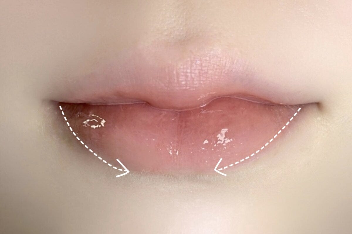 下唇の口角から中央へリップを薄く塗る方向を矢印で示した手順