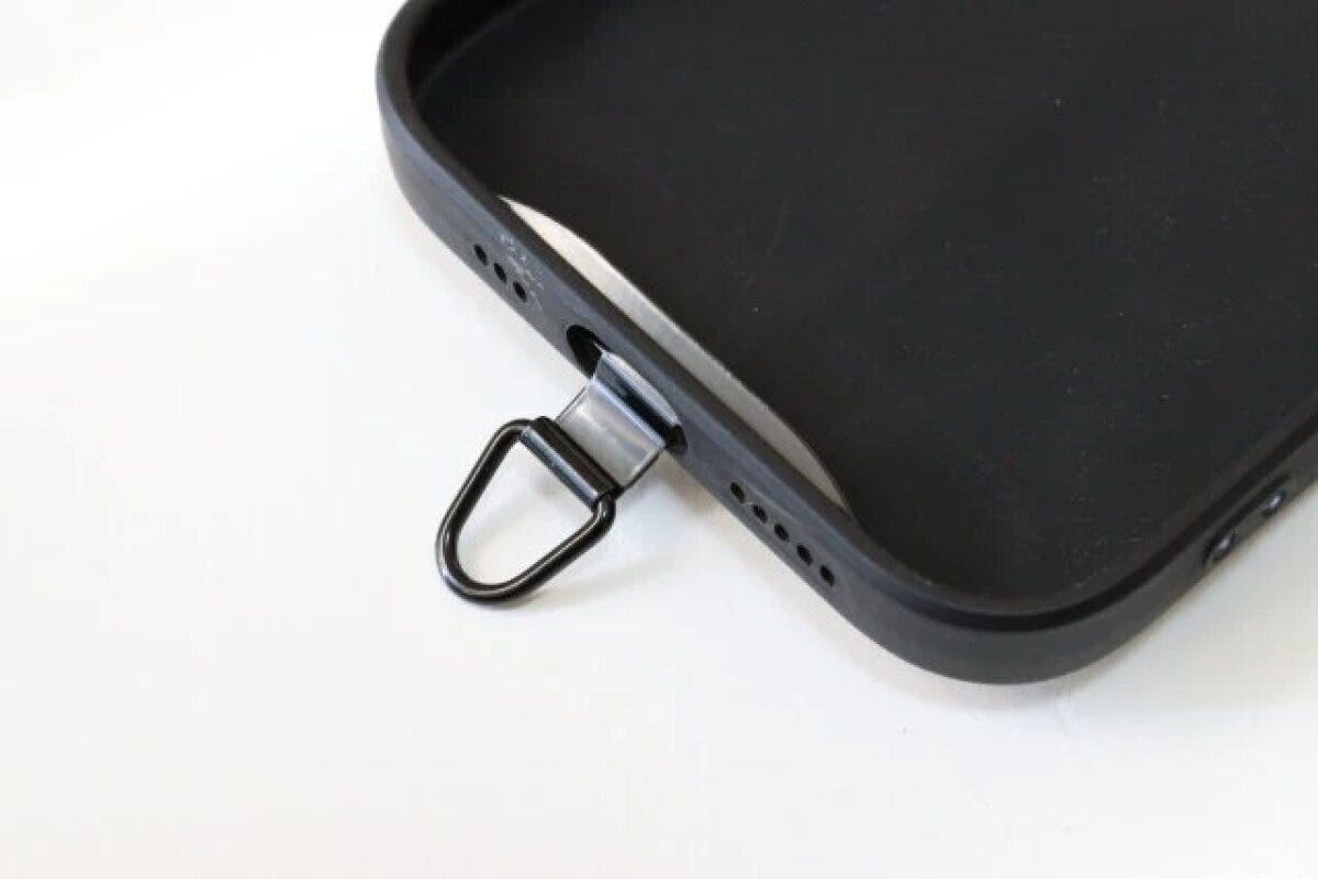 黒いスマホケースの充電口に装着されたストラップホルダー