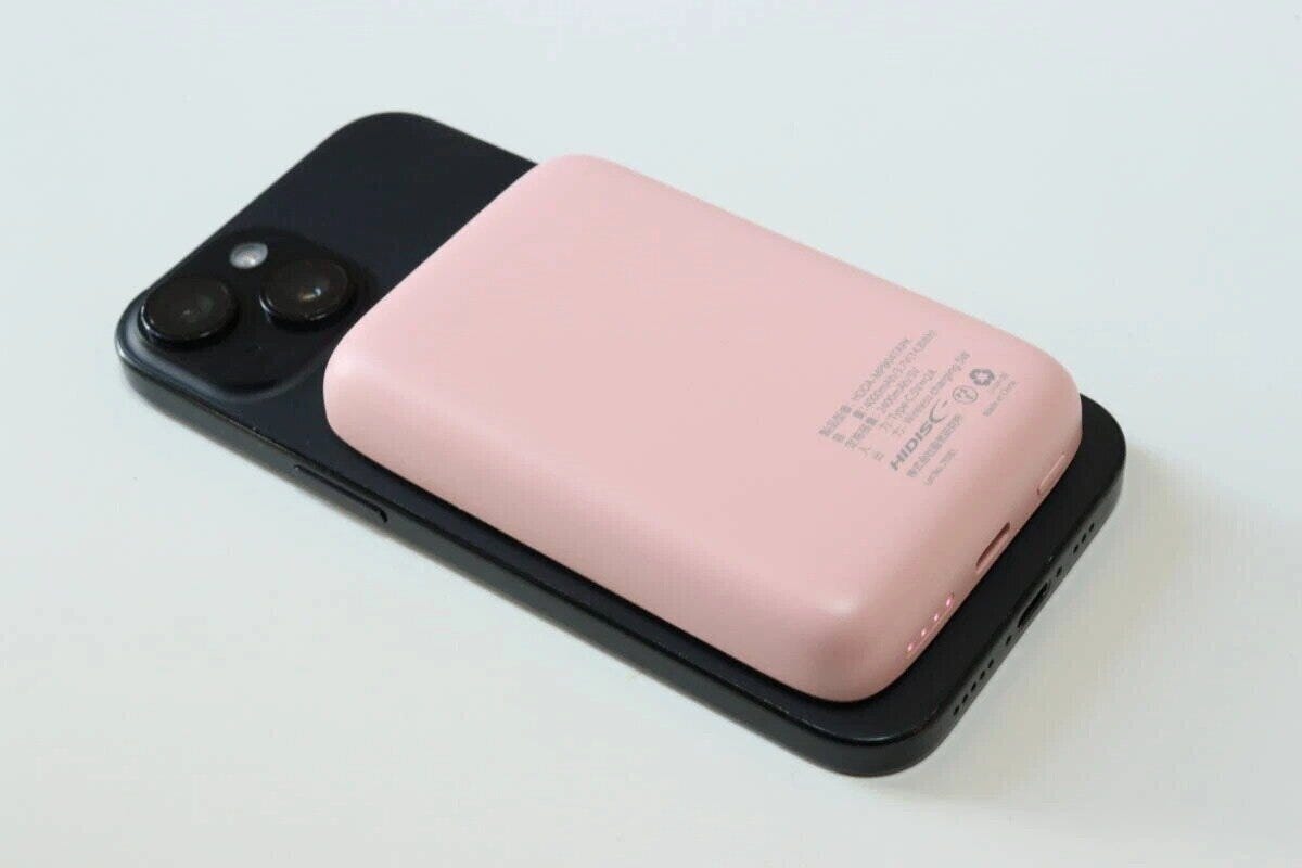 ピンクのモバイルバッテリーを黒いスマートフォンに重ねて充電している ピンクのモバイルバッテリーを黒いスマートフォンに重ねて充電している