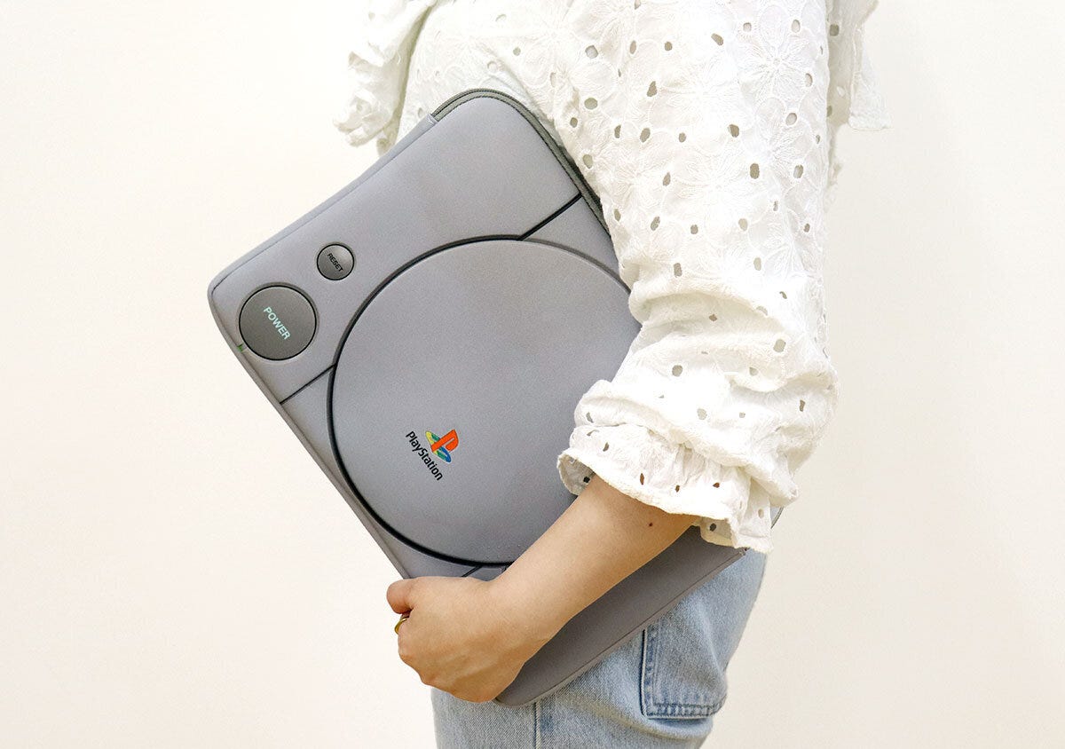 白い服の女性が初代プレステ型ケースを脇に抱えて歩く