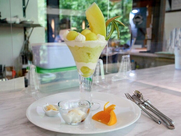 ル・パルフェ馬車道「マスクメロンのパフェ」（税込2420円）。お口直しのパルジャミーノ・レッジャーノ、パンナコッタ、オレンジ付き（2022年6月30日撮影）