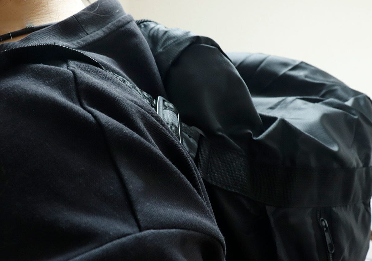 黒いTシャツの人がバッグをリュックとして背負っている