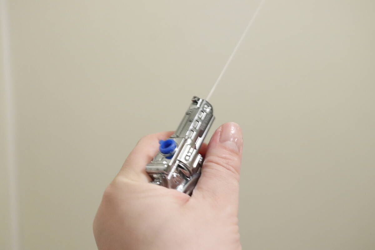 手に持った水鉄砲キーホルダーから勢いよく水が一直線に発射される