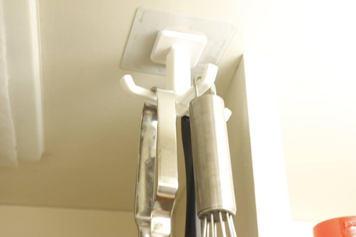 キッチン戸棚の下に設置した回転フックに泡立て器とトングを吊り下げた様子 キッチン戸棚の下に設置した回転フックに泡立て器とトングを吊り下げた様子