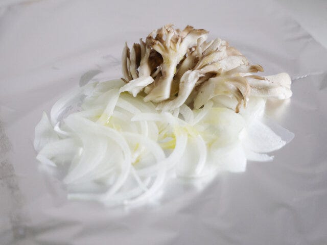 アルミホイルの中央に玉ねぎを広げ、きのこを添えてオリーブオイルをかける。