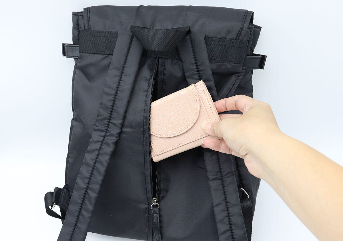 リュックの背面ファスナーを開けて財布を取り出している様子