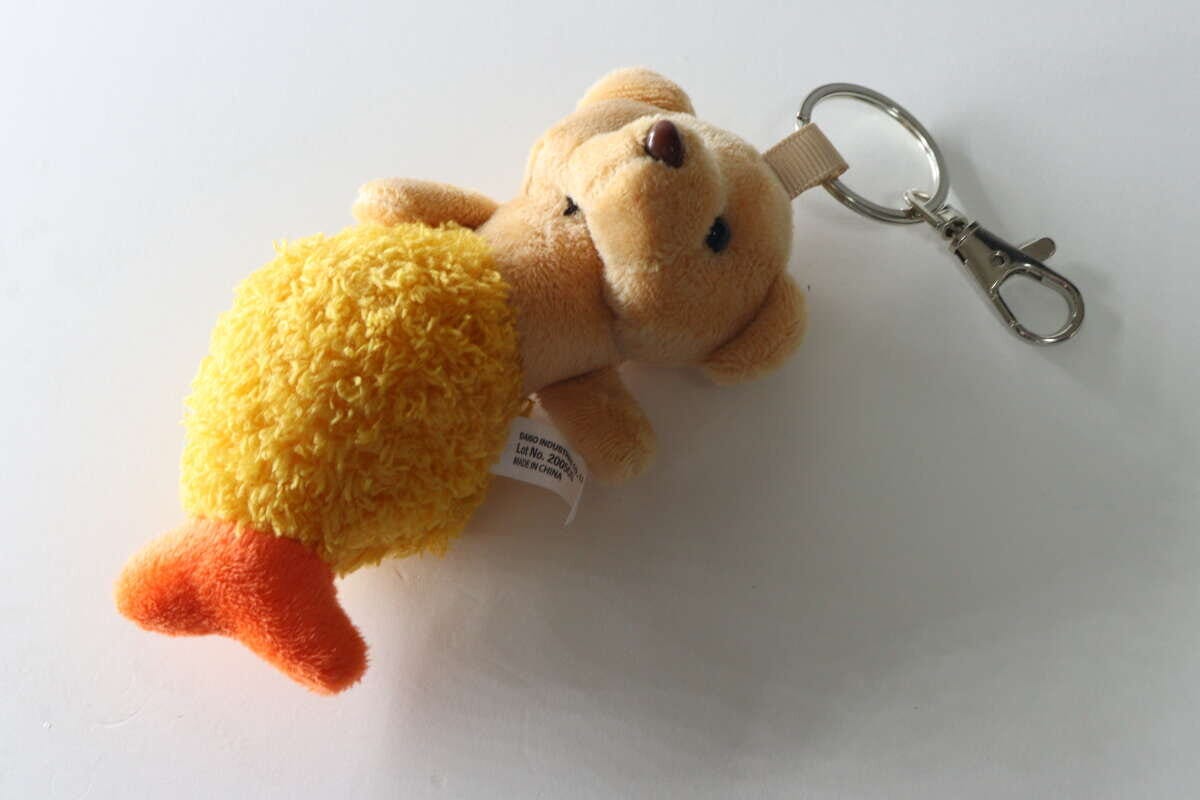 白い背景に置かれた、エビフライくまキーホルダーの裏側と金具
