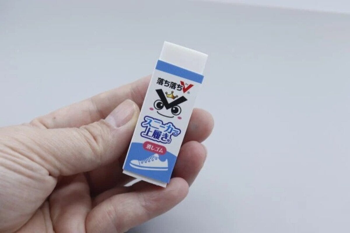 「落ち落ちV」と書かれたスニーカー＆上履き用消しゴムを女性が指でつまんで持っている