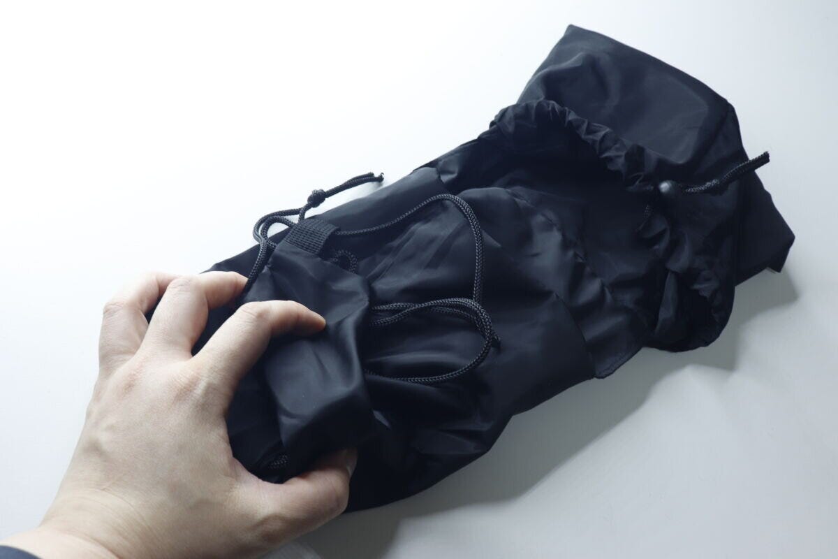 広げたナップサックを畳んで巾着型に戻している手元