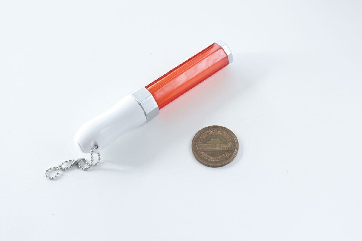 赤いミニペンライトキーホルダーと10円玉が並べて置かれている