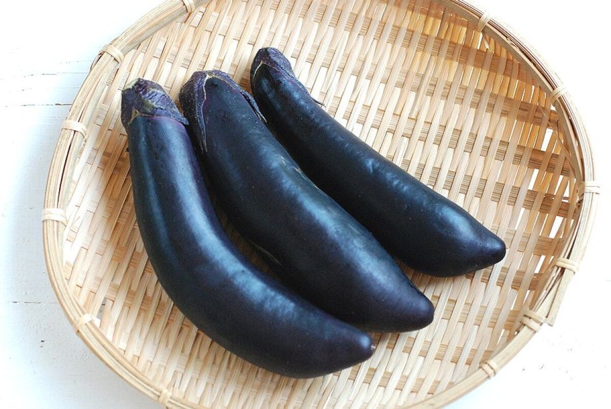 竹ざるに盛られた3本のつややかな紫色のなすの俯瞰