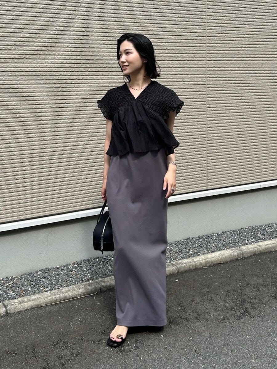 黒ブラウスとグレーのキャミワンピースを重ね着した女性の全身 黒ブラウスとグレーのキャミワンピースを重ね着した女性の全身