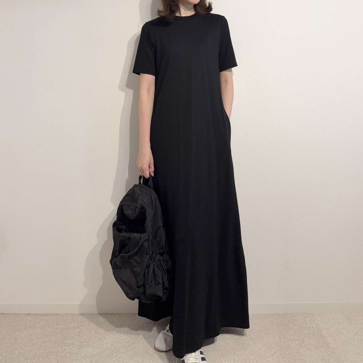 黒いワンピースに黒いリュックとスニーカーを合わせた女性の全身