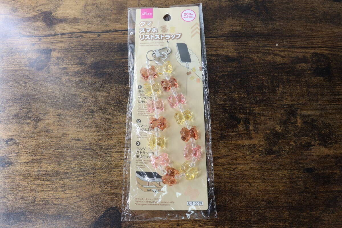 木目のテーブルに置かれたスマホリストストラップのパッケージ 木目のテーブルに置かれたスマホリストストラップのパッケージ