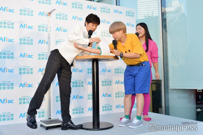 不思議な体勢でまひる(右)の血圧をはかる田中圭(左)/(C)モデルプレス