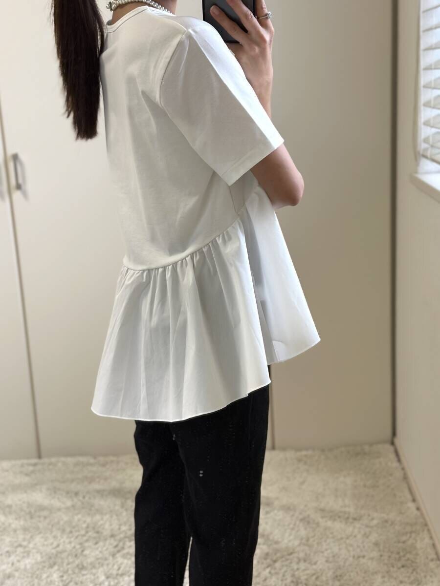 白いペプラムTシャツと黒パンツを着た女性の横向き