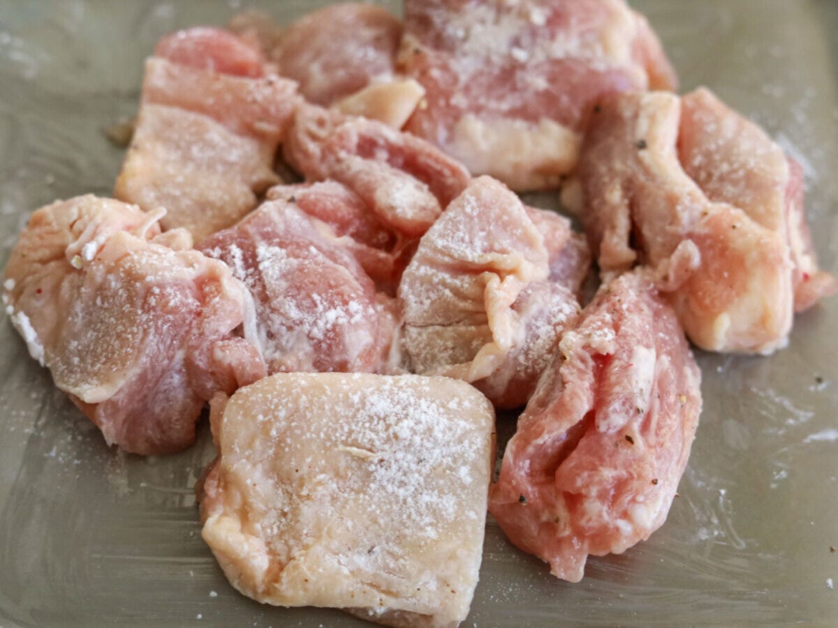 片栗粉をまぶした鶏もも肉 一口大に切った鶏もも肉に片栗粉をまぶし、白い粉がついた状態のアップ写真