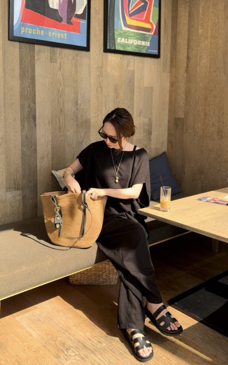 カフェのベンチに座りバッグの中を見る黒い服の女性 カフェのベンチに座りバッグの中を見る黒い服の女性