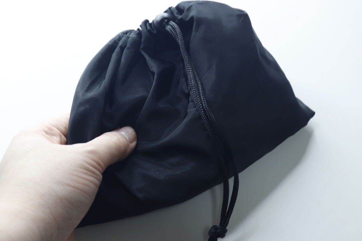 手で黒い巾着型ナップサックを握って持っている様子