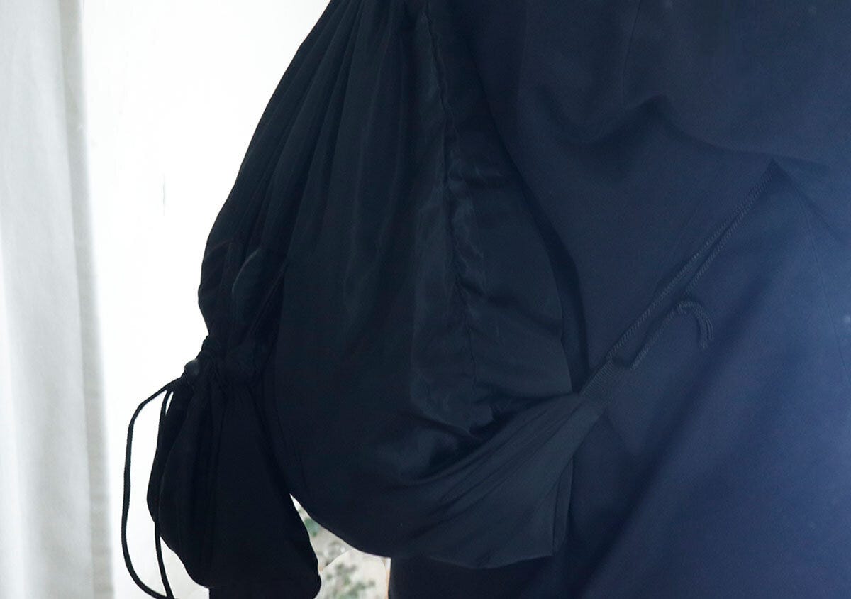 黒いナップサックを背負っている人の上半身と腕