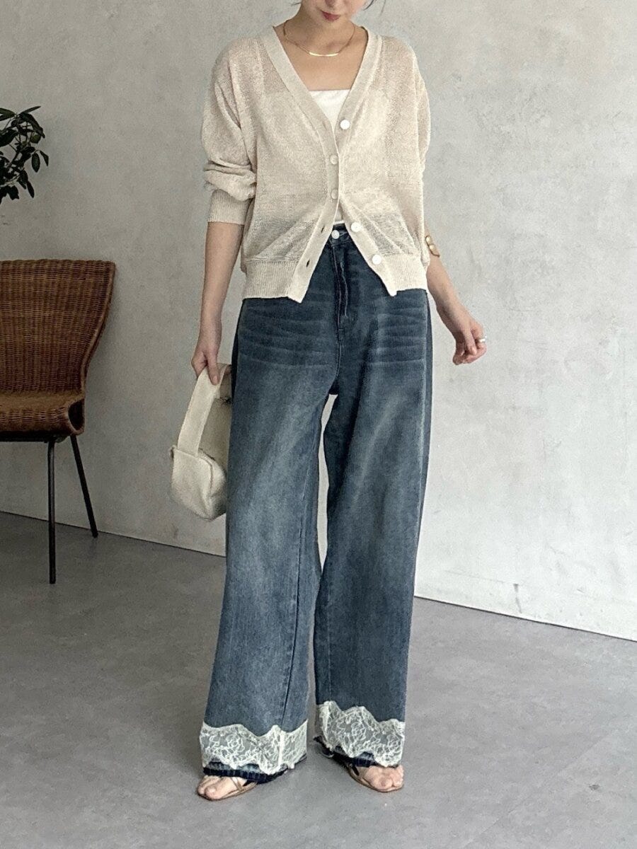 ベージュの透け感ニットカーディガンと裾レースデニムの女性