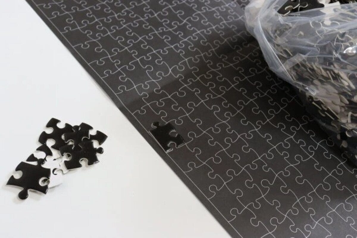 黒いパズルの参照紙と、その上に置かれた数個の黒いピース