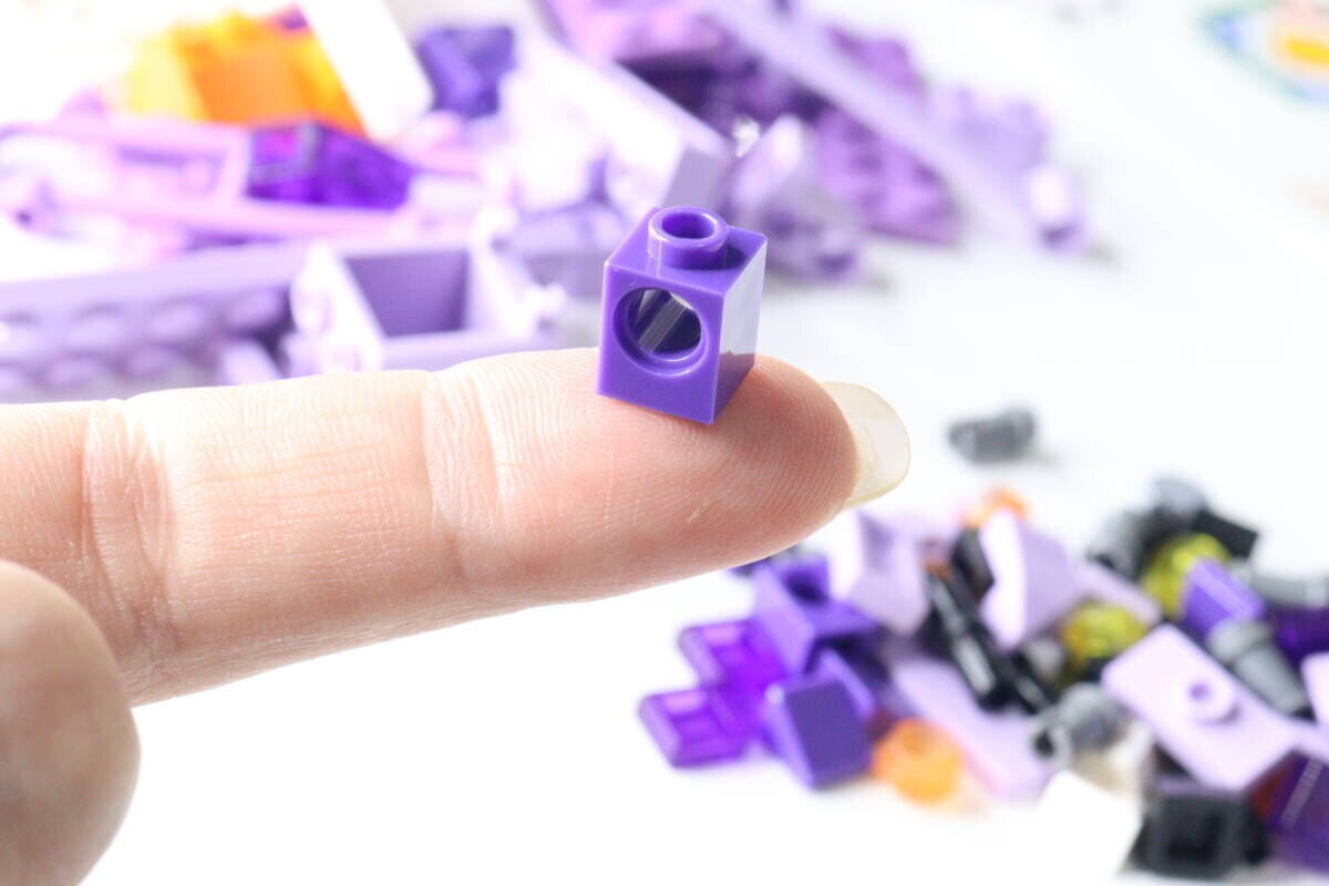 人差し指の先に乗せられた小さな紫色のブロック 人差し指の先に乗せられた小さな紫色のブロック