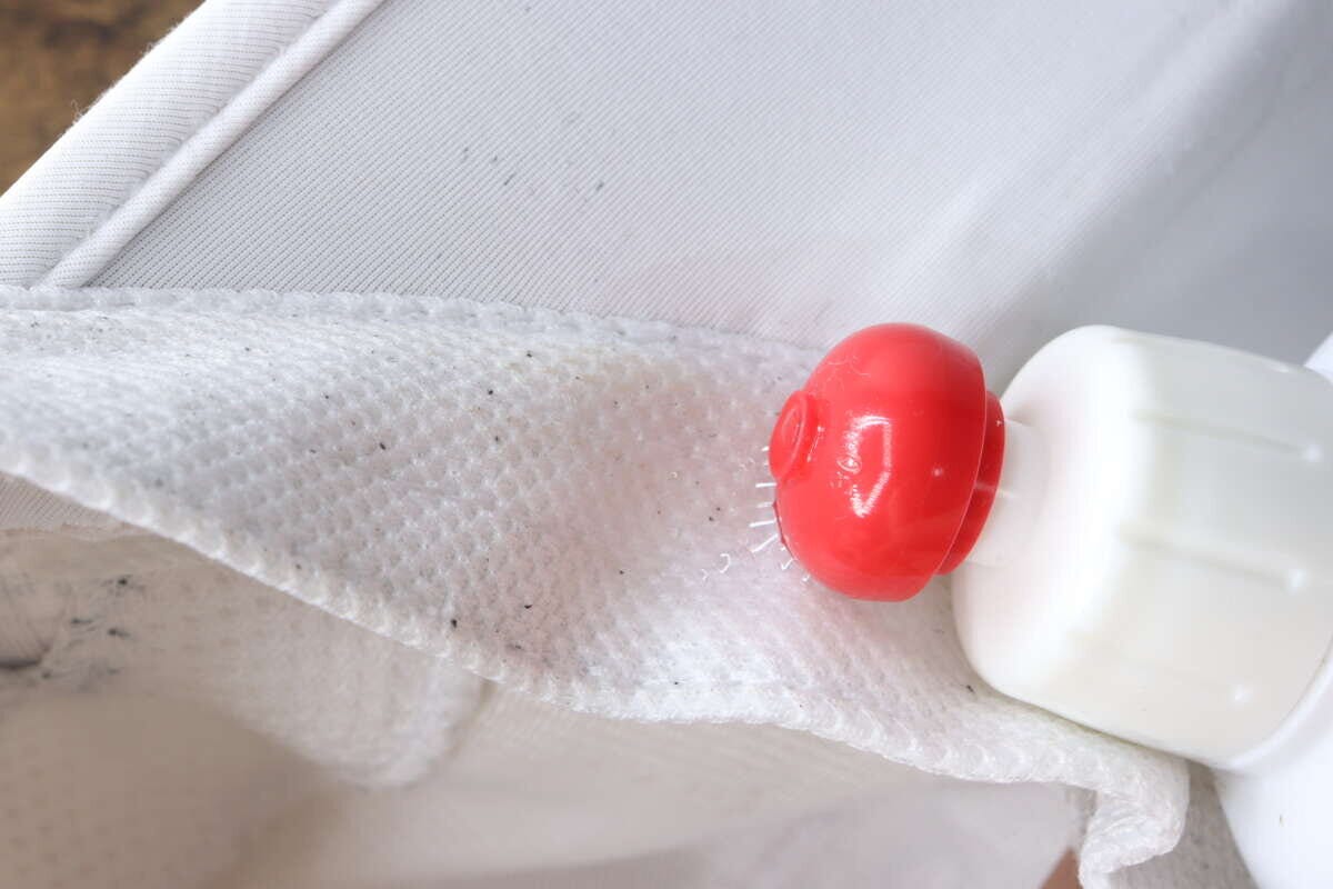 帽子の内側の黄ばんだ部分に洗剤の先端を当てて塗布している