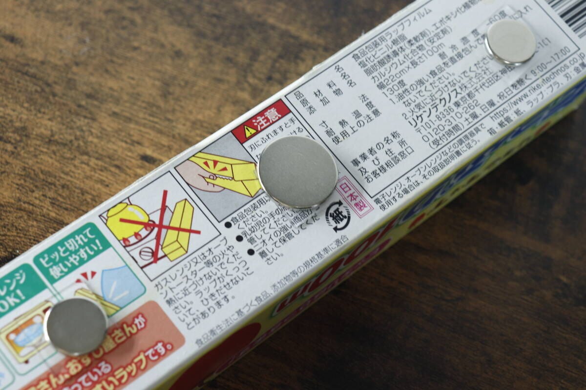 ラップの箱の側面に丸いマグネットを貼り付けている様子