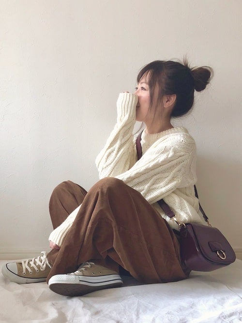 白ニット×ブラウンパンツ×ベージュコンバースの女性が横向きで座っている画像