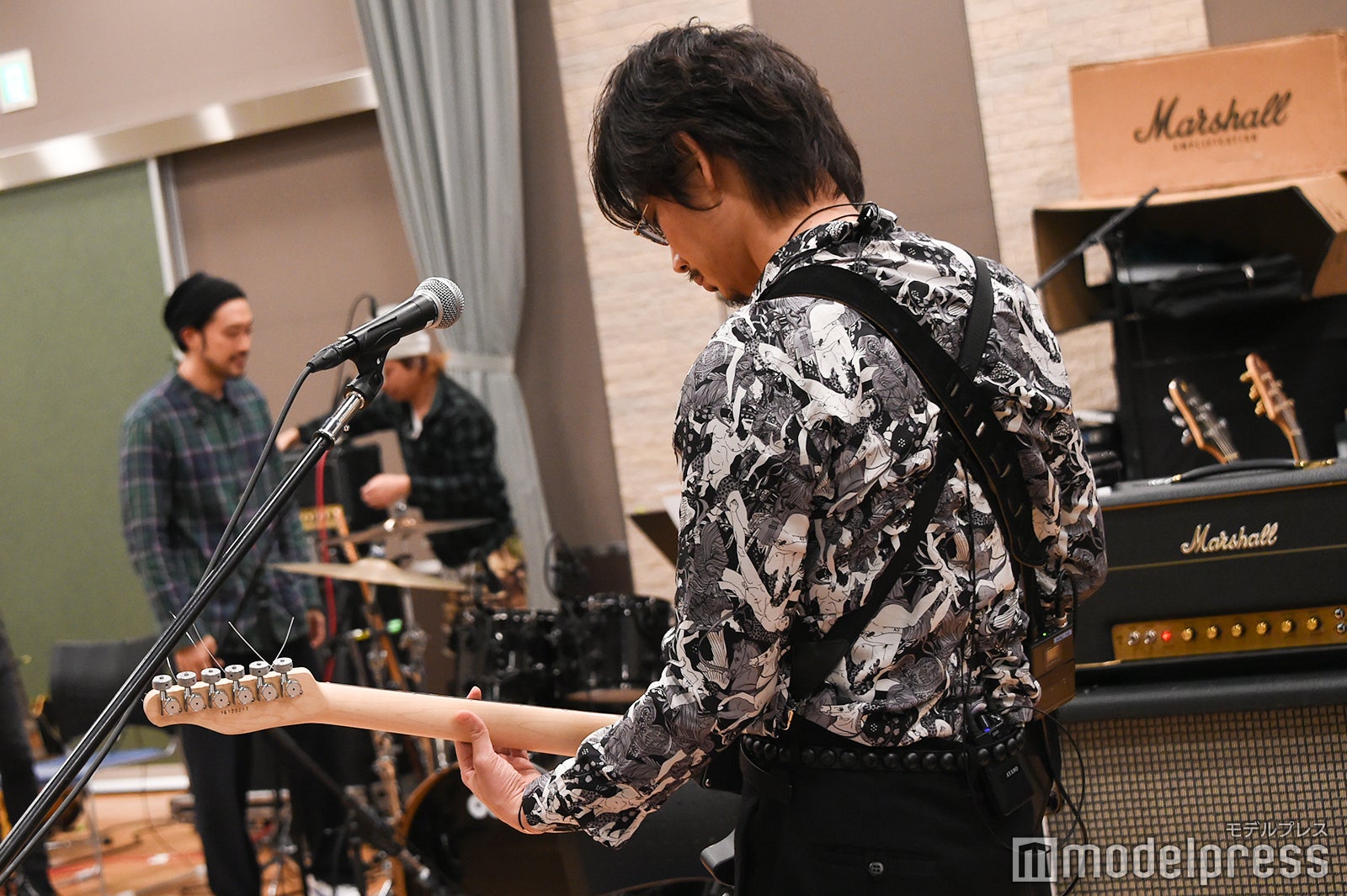 ギターを弾く綾野剛の後ろ姿 （C）モデルプレス