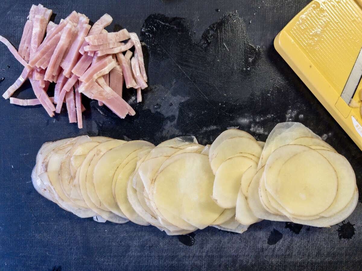 細切りにしたベーコンと、スライサーで皮ごと薄くスライスした新じゃがいもをまな板に並べた様子