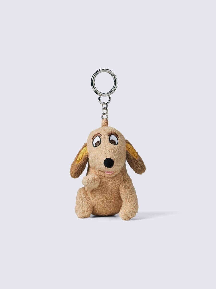 茶色の犬のぬいぐるみ型チャーム。つぶらな瞳で座っている 茶色の犬のぬいぐるみ型チャーム。つぶらな瞳で座っている