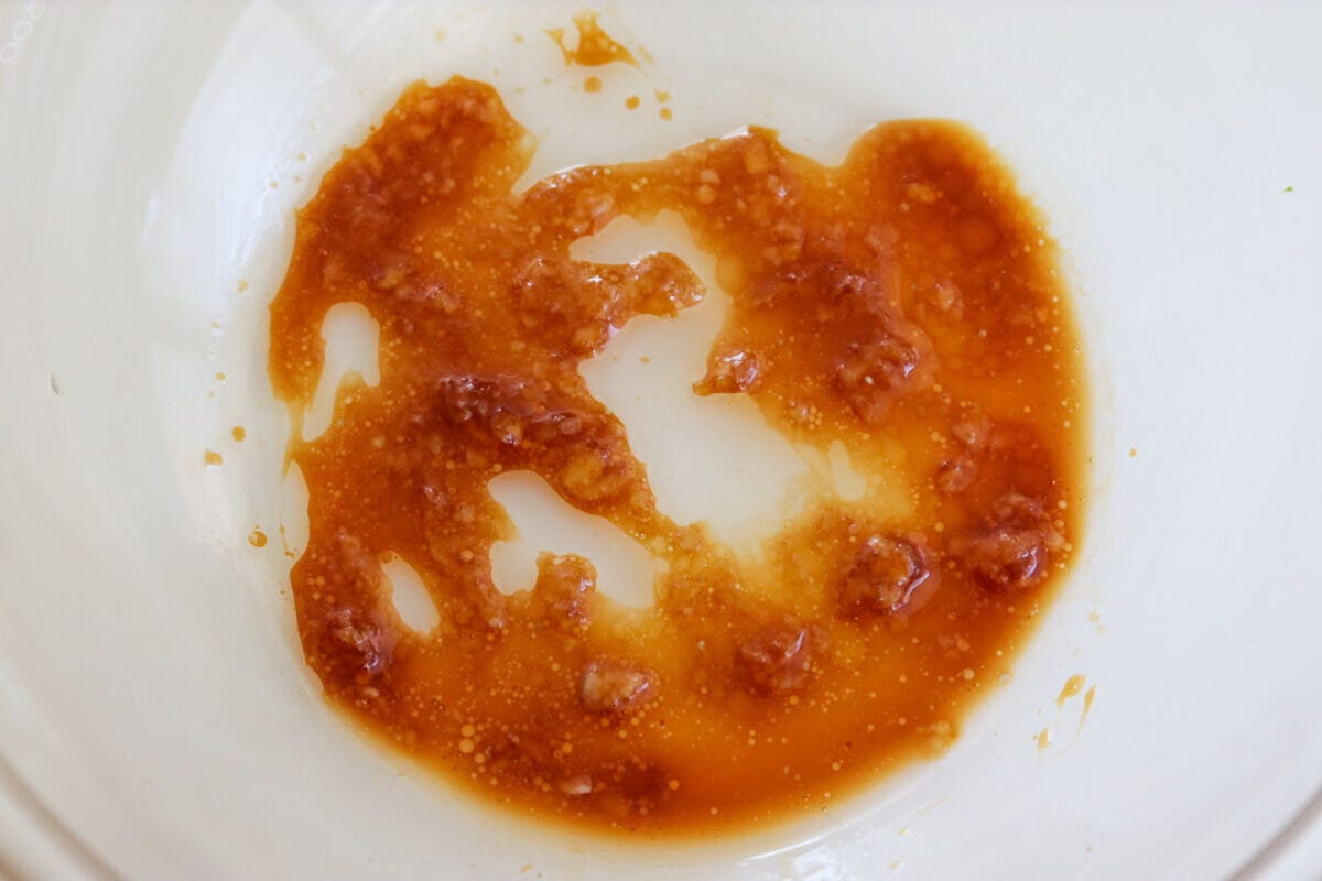 透明なボウルに、しょうゆ、砂糖、にんにく、ごま油を混ぜ合わせたタレが入っている様子 透明なボウルに、しょうゆ、砂糖、にんにく、ごま油を混ぜ合わせたタレが入っている様子