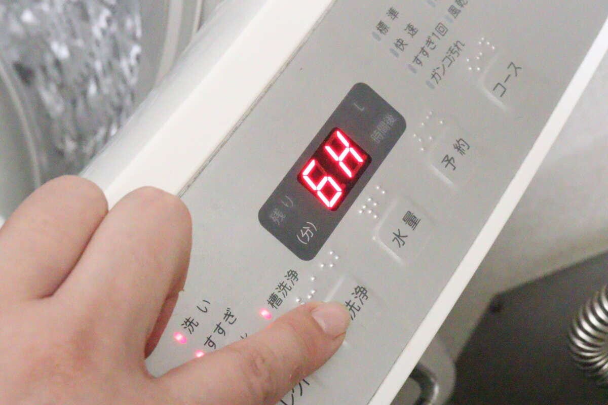 洗濯機の操作パネルで「槽洗浄」ボタンを押す指